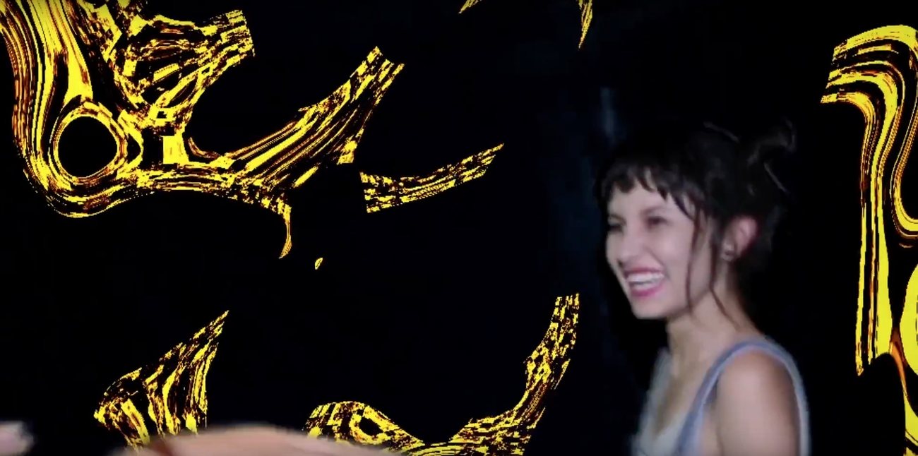 Dancer smiling against a black wall with yellow painted motifs