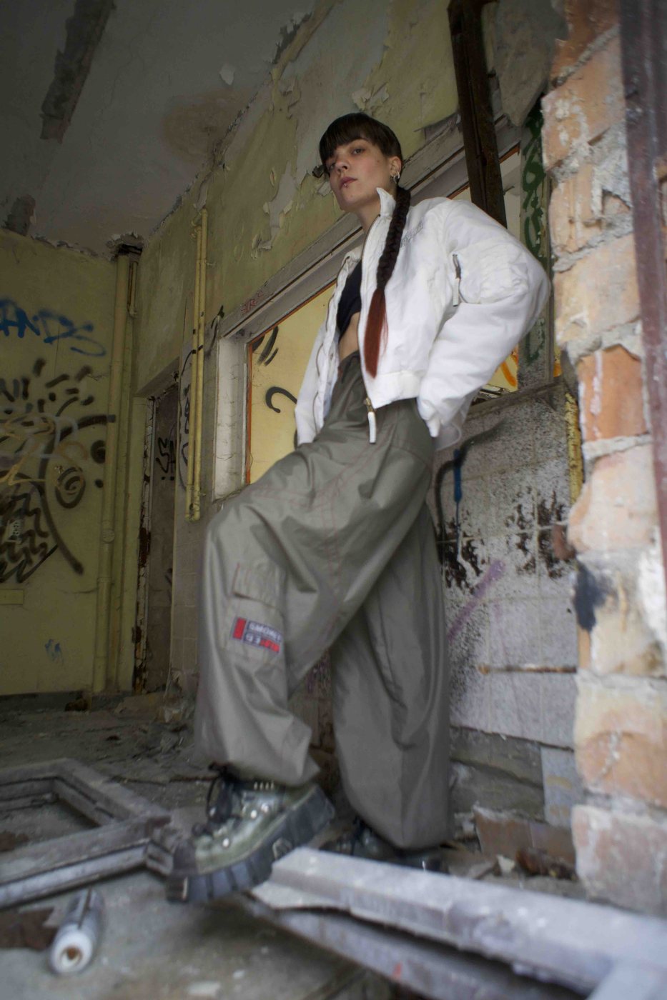 Inner Rave — low-angle shot of a model in a white jacket and grey trousers in a stairwell