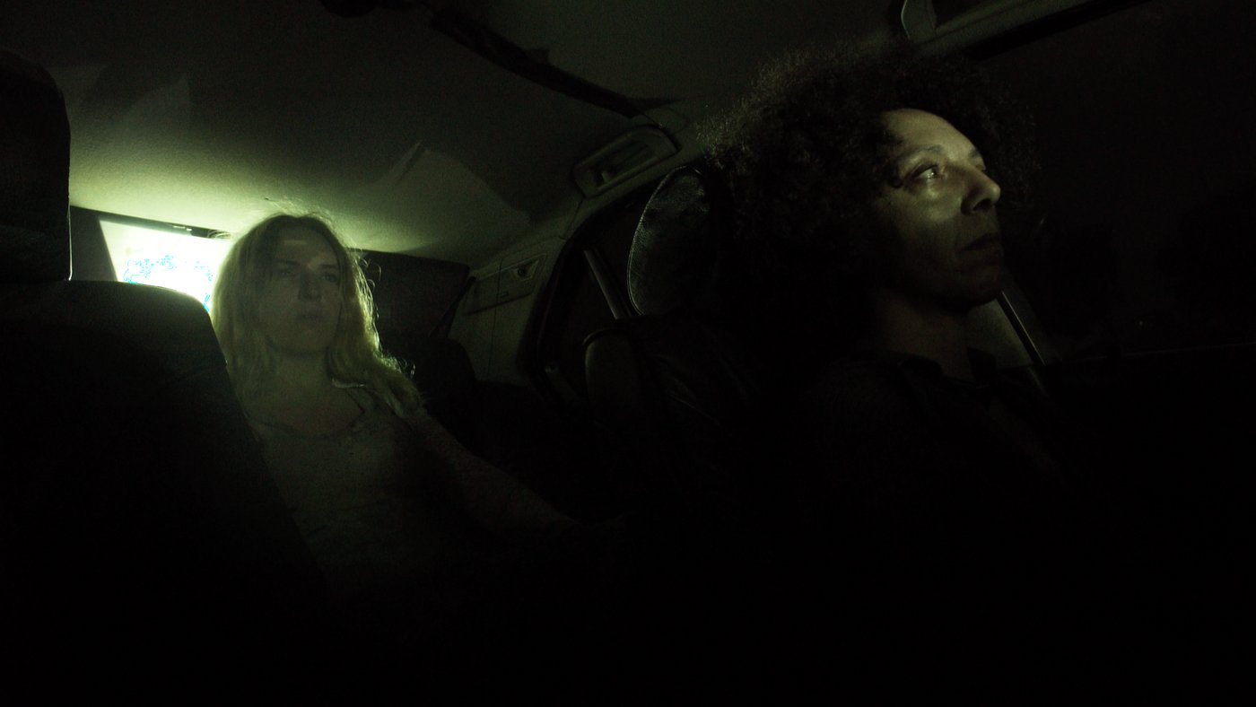Ohnmacht — two characters inside a car at night, lit green