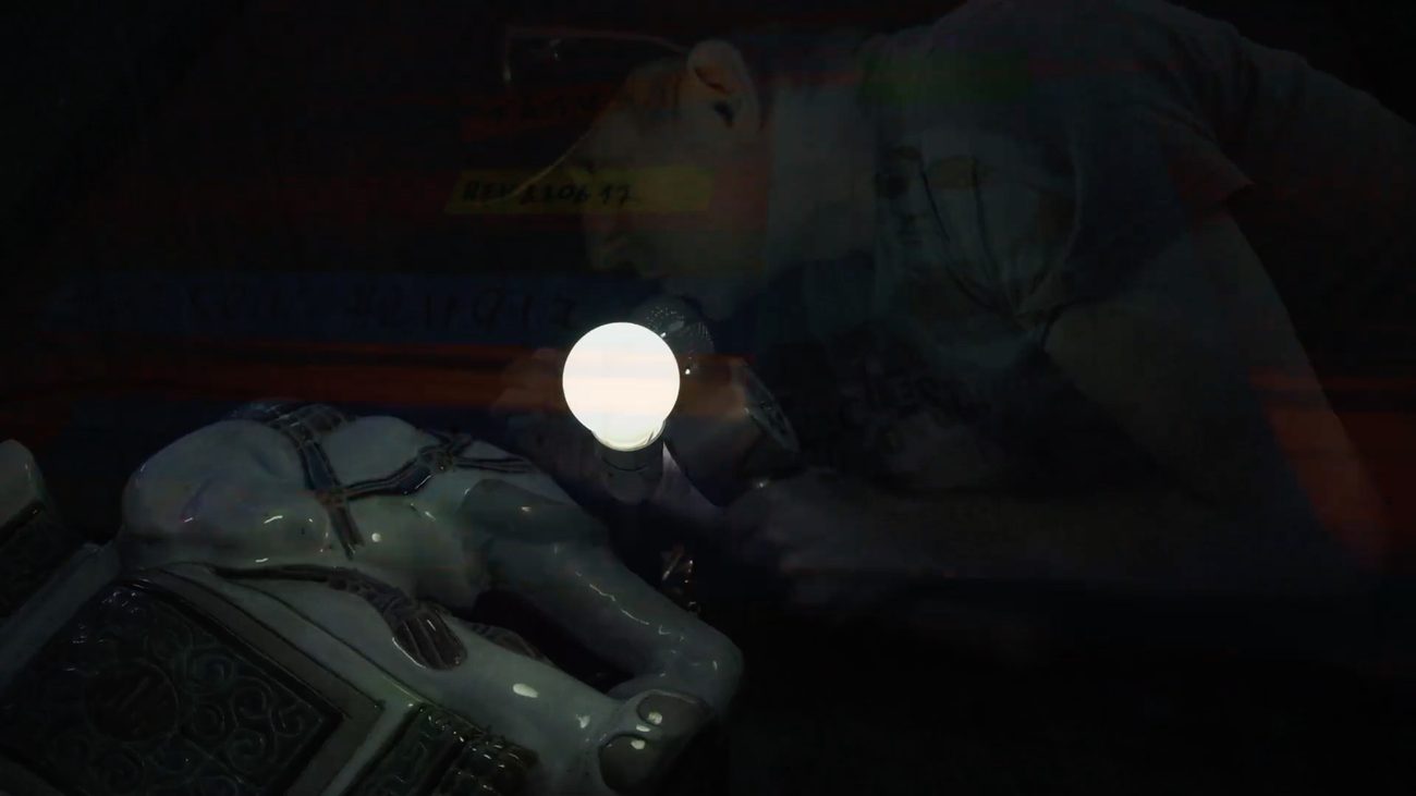 T.A.T.V. — a performance detail lit by a single bulb, overlaid visuals